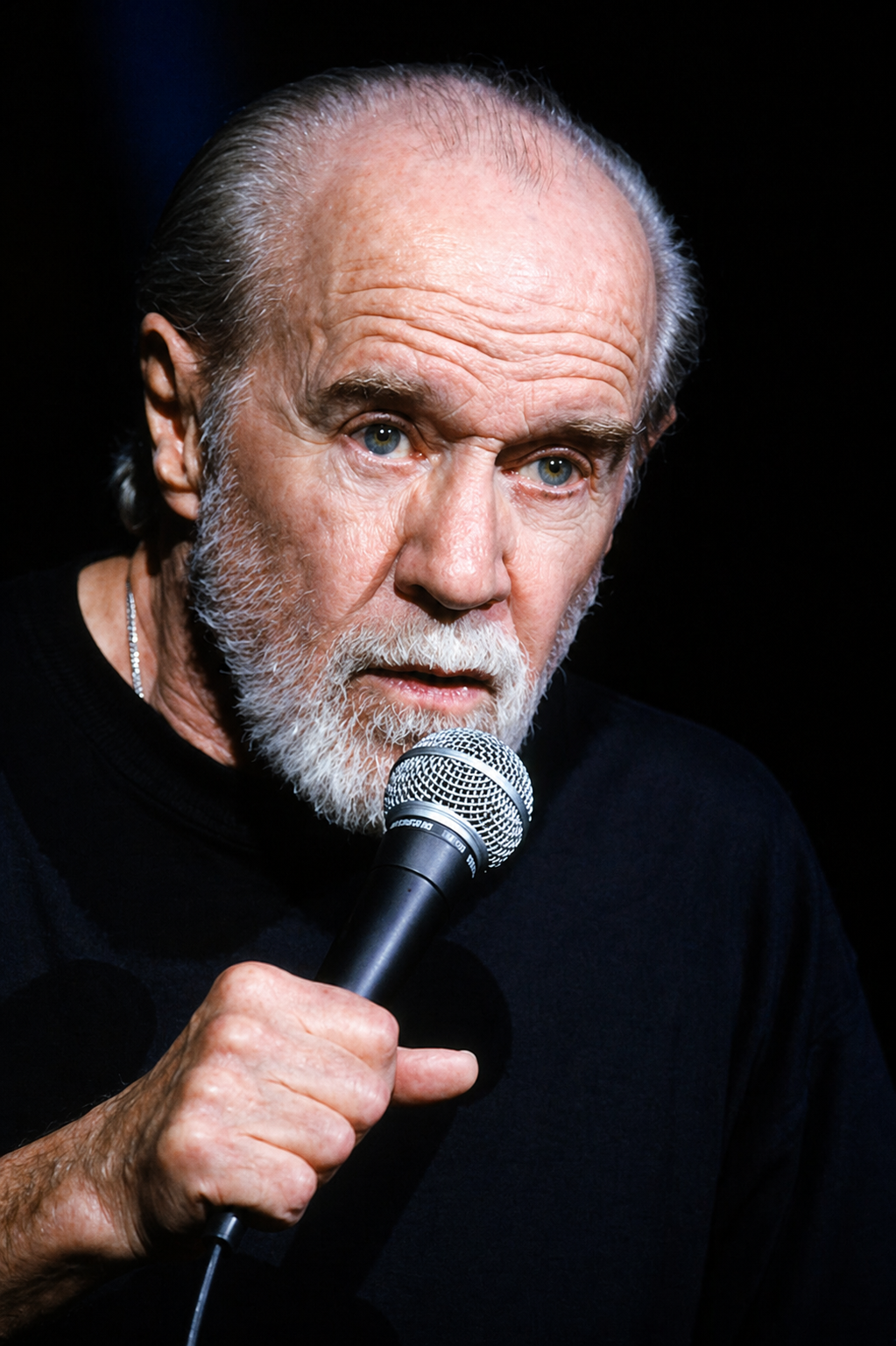 George Carlin performing onstage with a microphone